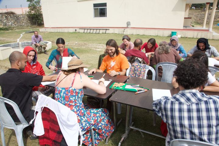 Grown-ups drawing at tables on a lawn, Rishikesh