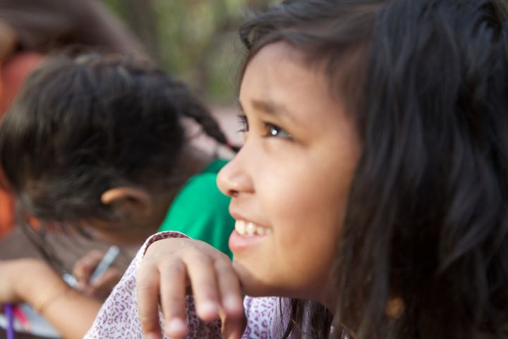 A girl looking up and smiling while she draws her alien, Rishikesh